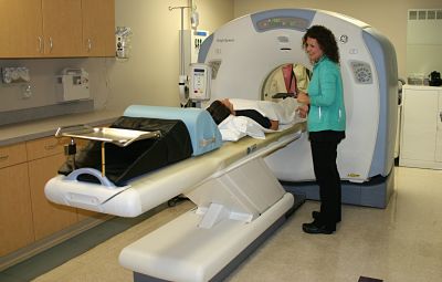 a patient is laying on the table getting ready to have a CT scan while the nurse is speaking with the patient.