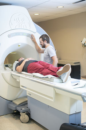 a patient is laying on the MRI table with a nurse speaking to the patient